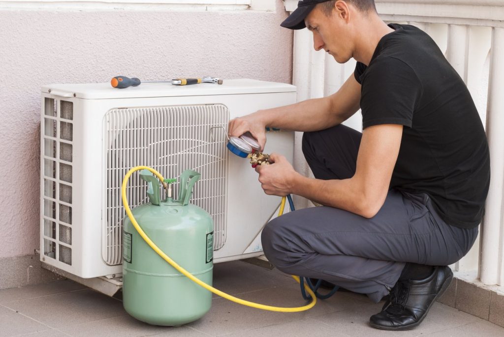 a man measuring the freon gas amount in an air conditioner